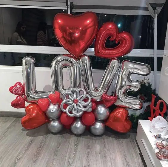 Valentine balloon bouquet with LOVE displayed in silver balloon letters topped with red heart balloons on a red and silver balloon base