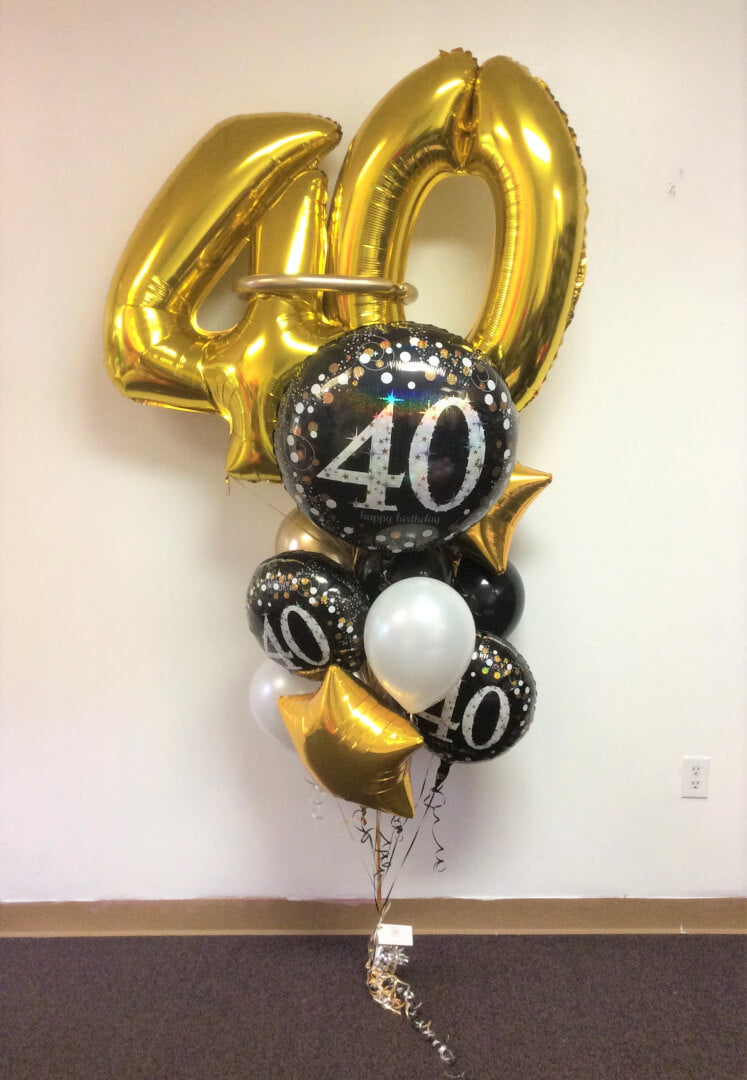 A balloon bouquet featuring large gold number 40 balloons, along with stars, black and white balloons with a 'Happy 40th Birthday' message.