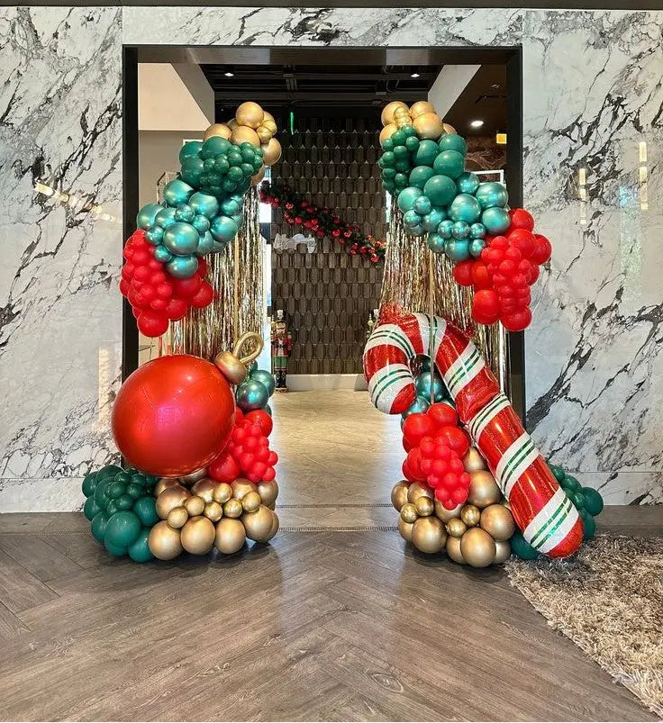 Decorative Christmas balloon arches in red, green, and gold at the entrance of a building.