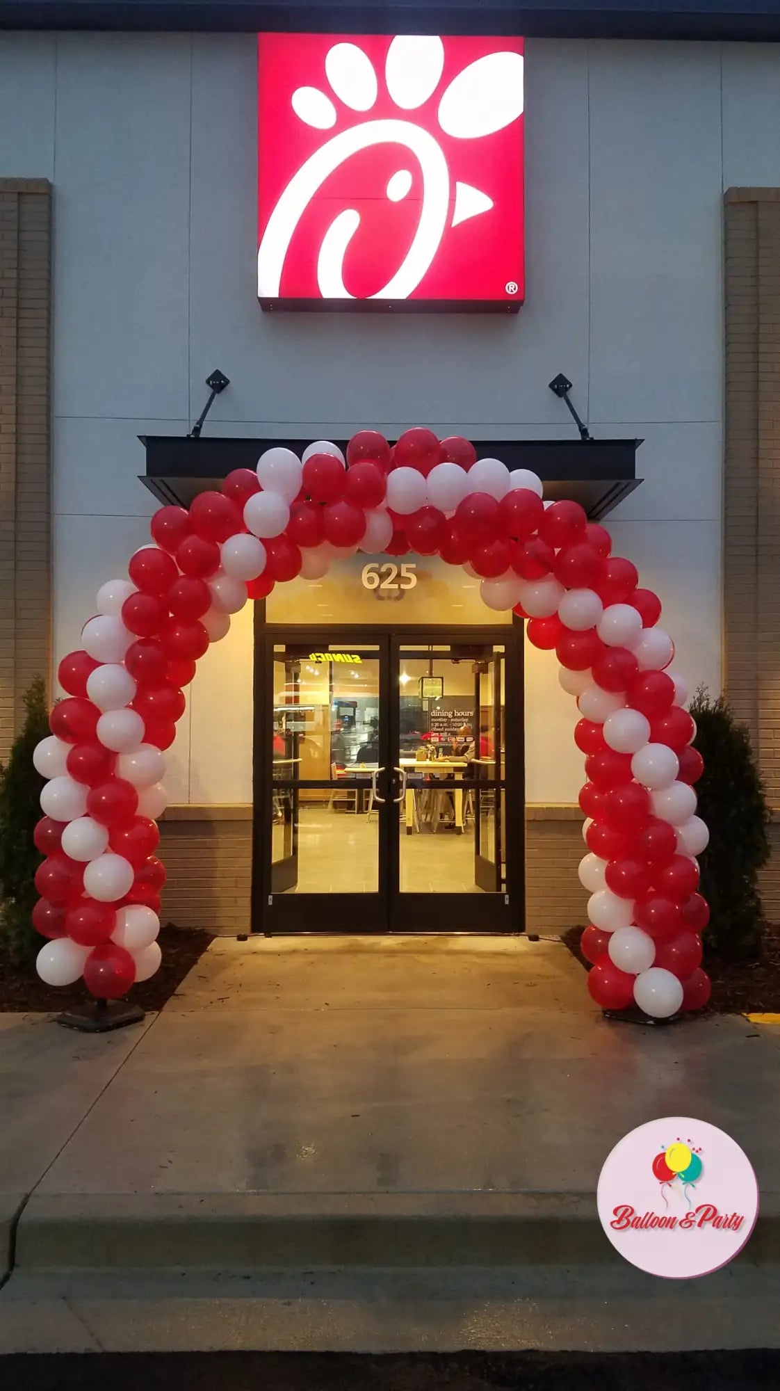 Red and white balloon archway above the entrance to a chick-fil-a restaurant.