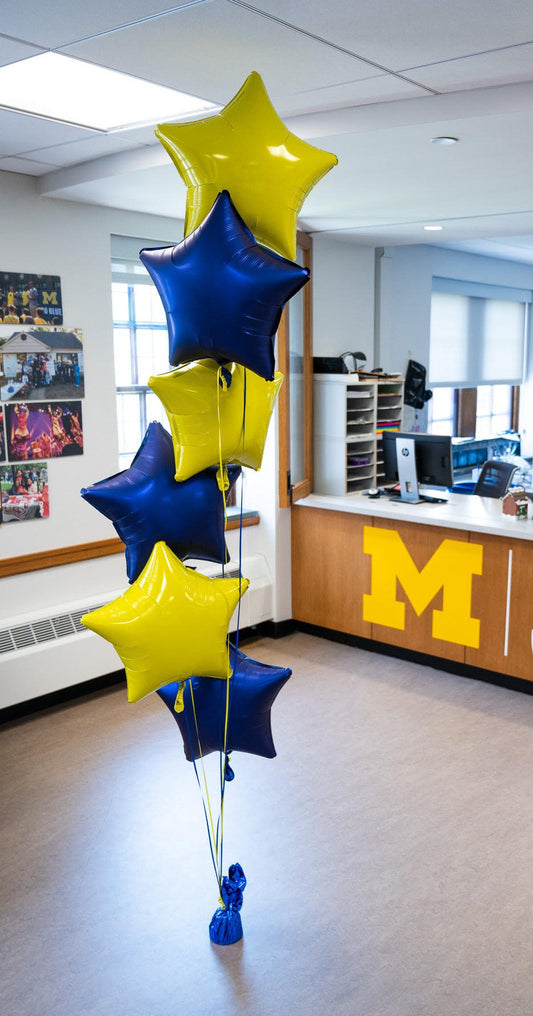 Yellow and blue star-shaped balloons in a bouquet bunch on a floor