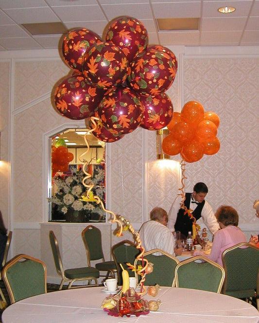 Thanksgiving themed centerpiece featuring fall leaves printed balloons in orange, yellow, and brown colors, displayed with a spiral stem on a stem