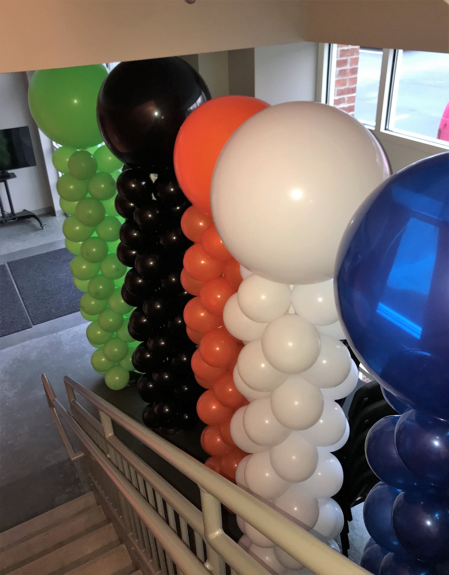 classic balloon columns green, black, orange, white and blue with big round balloons on top